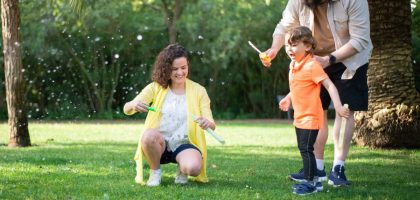 A family enjoys a playful day with bubbles in a sunny park setting.