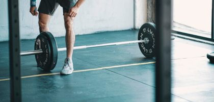 man in black t-shirt and black shorts holding black barbell