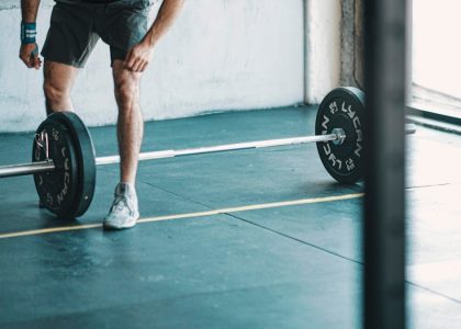 man in black t-shirt and black shorts holding black barbell